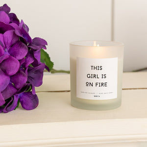 NIKITA Empowering white frosted glass candle, labelled 'This girl is on fire'. Featuring a white jasmine scent. Christmas or birthday home decor gift for her.